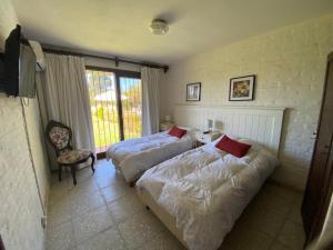 a bedroom with two beds and a chair and a window at Amplia, 4 dormitorios y piscina climatizada in Punta del Este +15 photos
