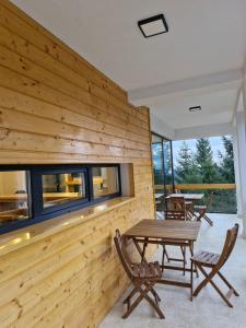 a room with a wooden wall with a table and chairs at Luna Retreat in Muntele Cacovei