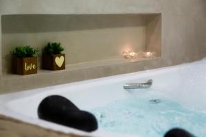 a bath tub with a faucet and some plants at Pousada Timoneiro in Ponta da Fruta
