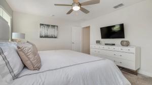a white bedroom with a white bed and a flat screen tv at La Casista in Orlando