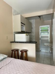 um quarto com uma cama e uma cozinha com bancos em Pousada na Lagoa da Conceição Barcelos em Florianópolis