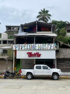 um camião branco estacionado em frente a um edifício em Pipeline Hostel em Puerto Escondido