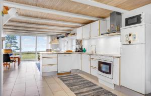 a kitchen with white cabinets and a large window at Cozy Home In Glesborg With Kitchen in Glesborg