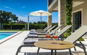 deux verres de vin sur une table à côté d'une piscine dans l'établissement Villa San Martino, à Rovinj