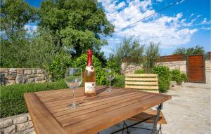 a bottle of wine sitting on a wooden table with two glasses at Three-Bedroom Holiday Home In Mratovo in Mratovo
