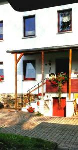 a white building with a red door and a plant at -Alirina- Ferienwohnung, 2 Schlafzimmern,Parkplatz in Oberkotzau