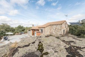 una casa in pietra con una grande roccia davanti di Finca privada 20 hectáreas con preciosa casa de campo a Navas de San Antonio