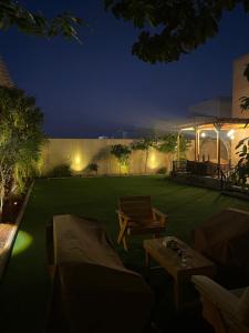 a backyard with a green lawn at night at Royal AlUla Villa in Al-ʿUla