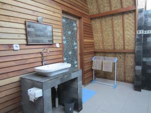 a bathroom with a sink on a wooden wall at Djamezz Lumbung in Gili Air