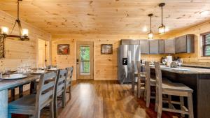 a kitchen with a long bar with chairs and a refrigerator at Star Ridge Cabin in Sevierville