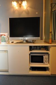 einen TV auf einem Stand mit einer Mikrowelle und einem TV in der Unterkunft Hotel Boston Club (Adult Only) in Tokio
