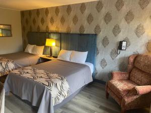 a hotel room with two beds and a chair at Village Inn of Hardy in Hardy