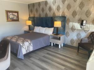 a bedroom with a bed and two lamps and a chair at Village Inn of Hardy in Hardy