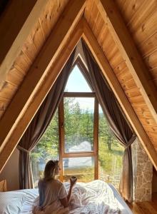 ジャブリャクにあるWonderwood Cabin 2の窓を見ながらベッドに腰掛けている女性
