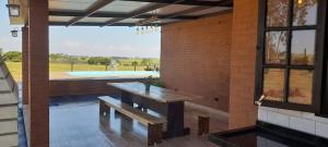 a patio with a wooden bench and a large window at Rancho Cata Vento in Santa Clara dʼOeste