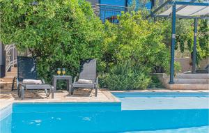 two chairs and a table next to a swimming pool at 1 Bedroom Lovely Apartment In Brodarica in Brodarica