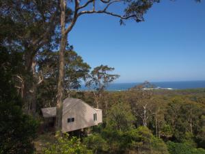 a house on a hill with the ocean in the background at Bundle Hill Cottages in Bawley Point
