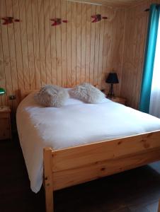 a bedroom with a wooden bed with white sheets at Cabaña los pajaritos de frutillar in Frutillar