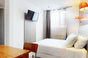 a bedroom with a bed and a table and a tv at Hôtel de Ménilmontant in Paris