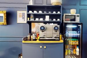 a counter with a coffee maker and a refrigerator at Hôtel de Ménilmontant in Paris