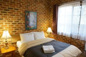 1 dormitorio con 1 cama grande y pared de ladrillo en Mahogany Park, en Cranbourne