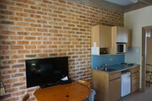 a kitchen with a table with a television and a brick wall at Mahogany Park in Cranbourne