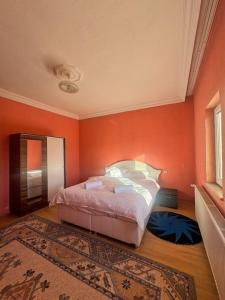 a bedroom with a bed with an orange wall at Kesen Cappadocia House in Urgup