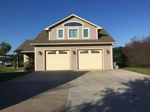 a house with two garage doors on a driveway at Hailey's Cottage on Small Farm-16 minutes to Silos in Bellmead