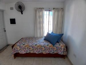 una camera da letto con un letto con un cuscino blu di RUTAC DEPARTAMENTOS- Departamento moderno con balcón a Las Grutas