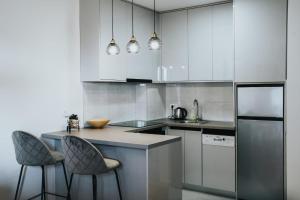 a kitchen with white cabinets and two bar stools at Apartman Riva in Čapljina