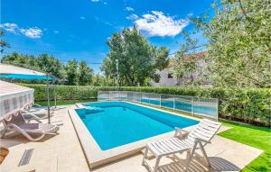 einen Pool in einem Garten mit zwei Stühlen und einem Sonnenschirm in der Unterkunft Gorgeous Home In Jadranovo With Kitchen in Jadranovo