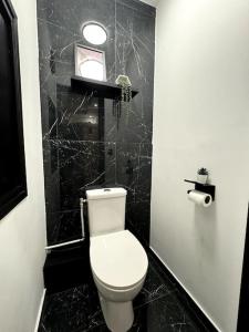 a bathroom with a toilet and a black tiled wall at Love Room, Luna Spa in Saint-Ouen-lʼAumône +15 photos