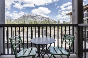 a table and two chairs on a balcony with a mountain at New 1Bd Luxe King Suite with Superb Mtn View in Canmore