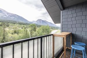 a balcony with two stools and a view of mountains at Stunning Silver Creek 1Br Mtn view penthouse in Canmore