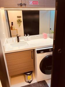 a bathroom with a sink and a washing machine at Serenity Bali Condotel in San Fernando