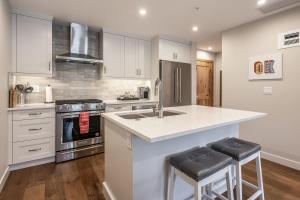 a kitchen with white cabinets and a kitchen island with bar stools at New 1Bd Luxe King Suite with Superb Mtn View in Canmore