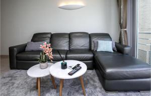 a living room with a black leather couch and two tables at Residentie Zeezicht in Ostend