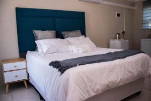 a large bed with white sheets and a blue headboard at Nsuku Guest House in Phalaborwa +15 photos