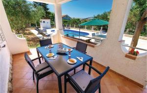a table and chairs on a patio with a pool at 2 Bedroom Gorgeous Apartment In Barbat in Barbat na Rabu