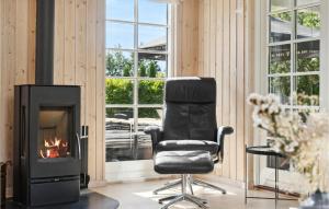 a black chair in a room with a fireplace at Cozy Home In Idestrup With Sauna in Marielyst