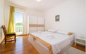 a white bedroom with a bed and a chair at Holiday Home Skabrnja 79 With Outdoor Swimmingpool in Galovac