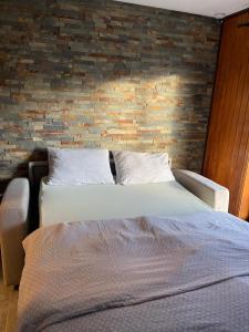 a bedroom with two beds and a brick wall at Le Skäli in Thollon