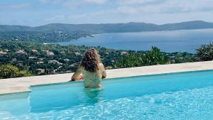 滨海卡瓦莱尔Villa Cacharelle Vue Mer Piscine的坐在游泳池里看着水面的女人