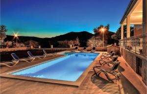 a swimming pool with lounge chairs and a house at Nice Apartment In Poljica in Poljica