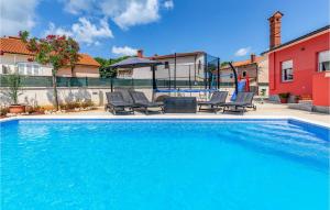 una grande piscina con sedie e una casa di 3 Bedroom Awesome Home In Marcana a Marčana