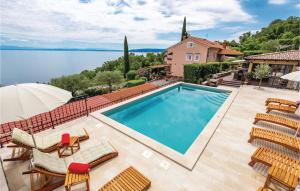 a pool with chairs and an umbrella and a house at Awesome Apartment In Moscenicka Draga in Kraj +31 photos
