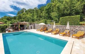 a swimming pool with chairs and umbrellas next to a stone wall at Awesome Apartment In Moscenicka Draga in Kraj