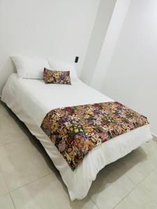 a white bed with a colorful blanket on it at Encantador y acogedor Apartamento in Filandia
