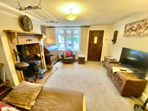 a living room with a couch and a flat screen tv at Bumblebee Cottage in Knowle +3 photos
