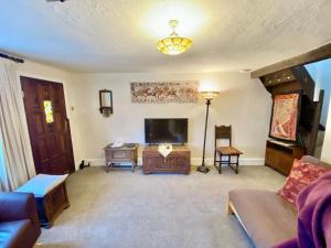 a living room with a couch and a television at Bumblebee Cottage in Knowle